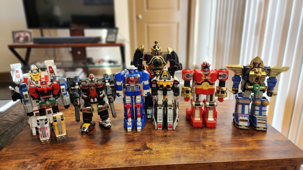 Eight Megazord toys. From left to right, in the front: Omega Megazord, Swat Megazord, Astro Megazord, Delta Megazord, Red Battle Zord, Zeo Megazord. Back: White Tigerzord, Thunder Megazord