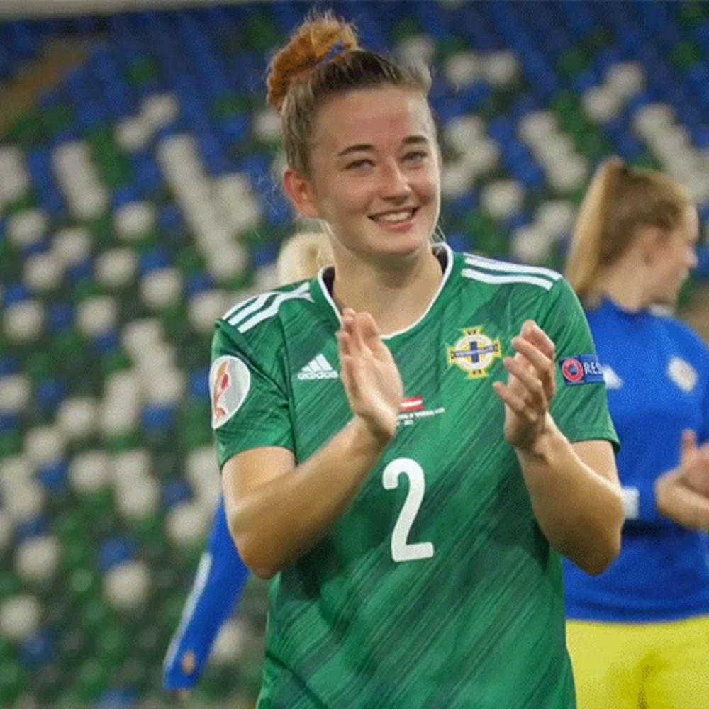 a woman wearing a green adidas jersey with the number 2 on it