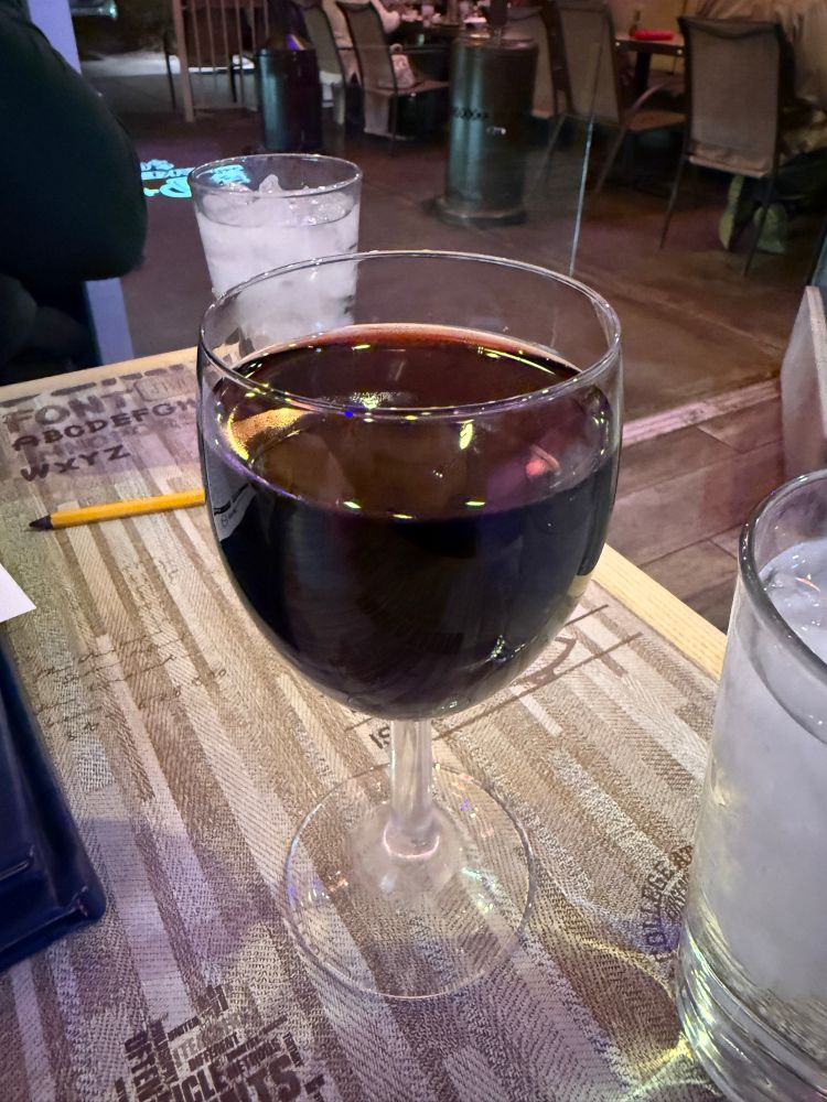A glass of red wine filled almost to the top