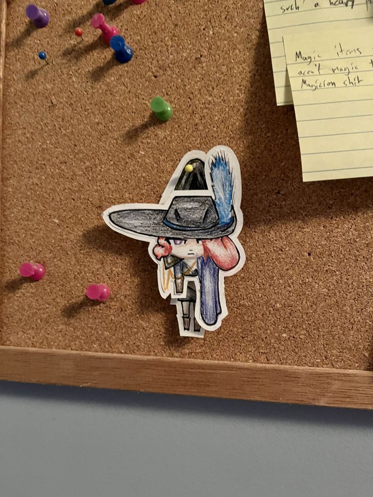 A paper doll of Damika in her musketeer outfit. She is pinned to a bulletin board by her cape and appears to dangling helplessly