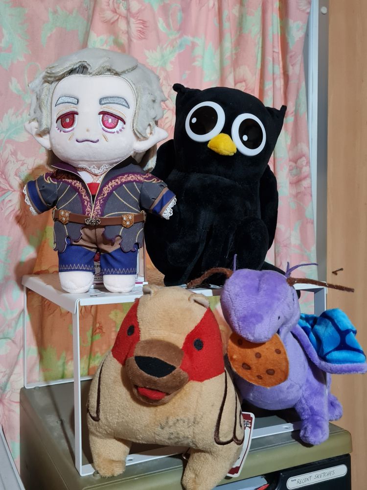 Plush toys of Baldur's Gate 3's Astarion, Dragon Age's Mabari Dog, Pathfinder: Wrath of the Righteous' Aivu, and Owlcat Games' Black Owlcat mascot