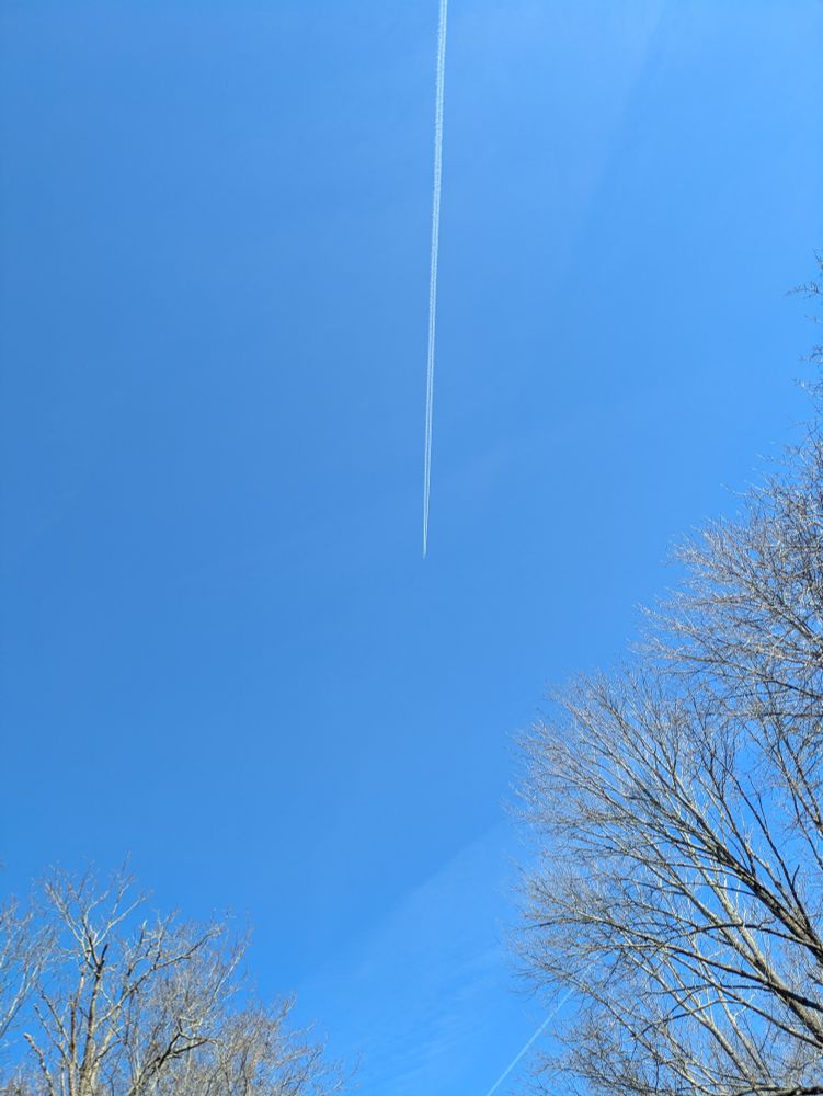 Condensation trail from a Europe-bound flight at cruising altitude over the East Coast