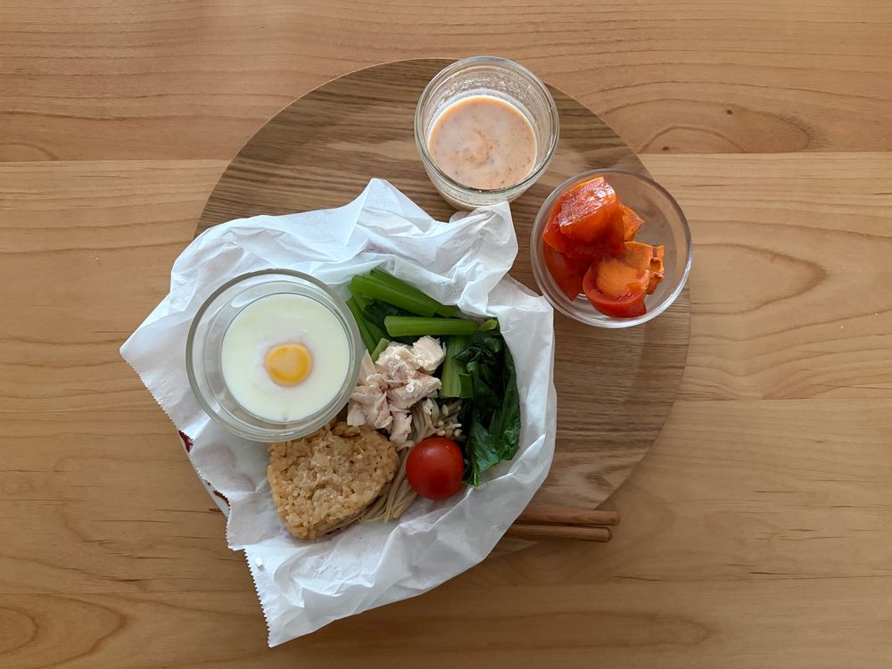 ペーパーを敷いた蒸し皿にポーチドエッグと小松菜とささみとミニトマトと茶色いおにぎり
グラスに柿ミルク、ガラス豆鉢に柿