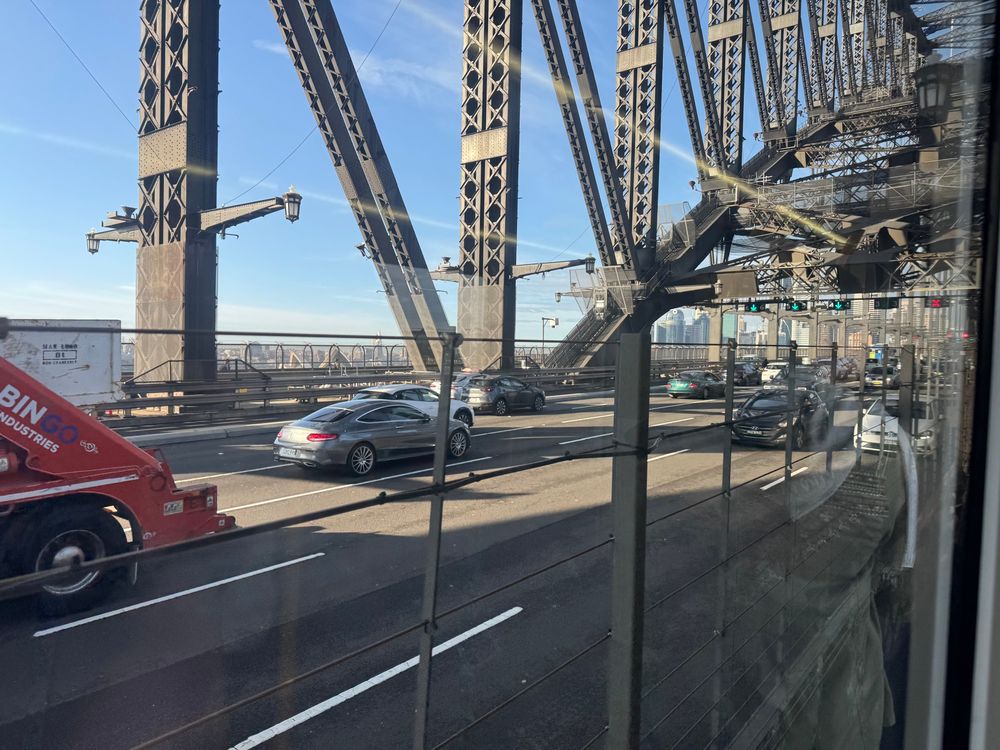 Cars crossing a steel arch bridge under a blue sky 