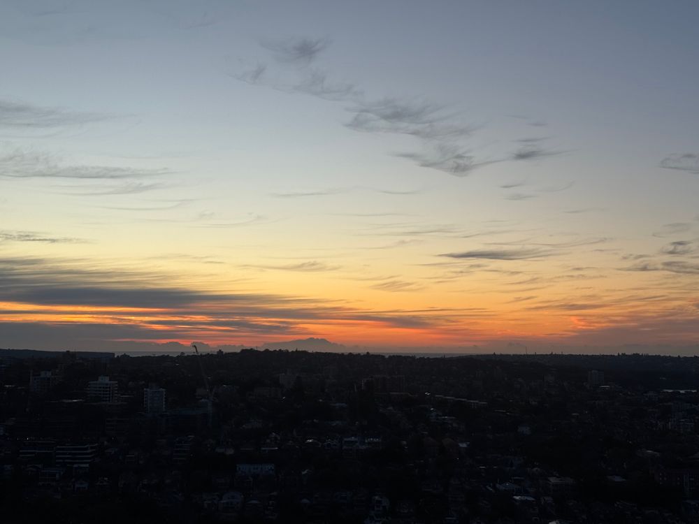 Slightly paler blue and orange sky over a darkened urban landscape 