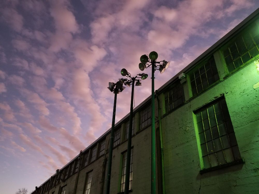 illuminated industrial/agricultural building against fading clouded sky