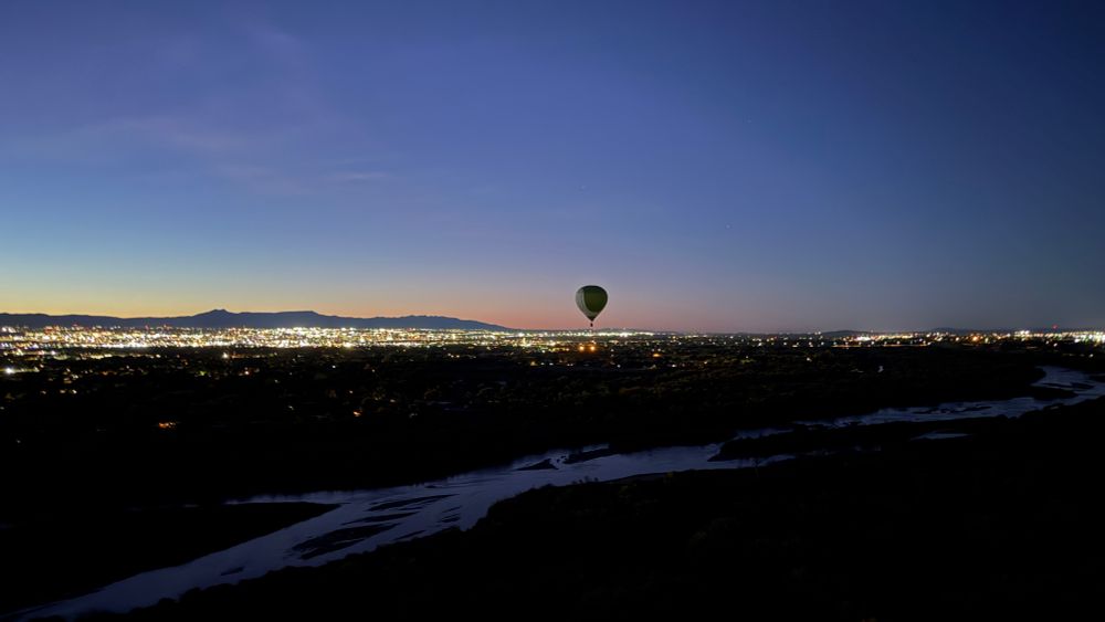 Balloon in the predawn skies over the Rio Grande river with city lights in the background 