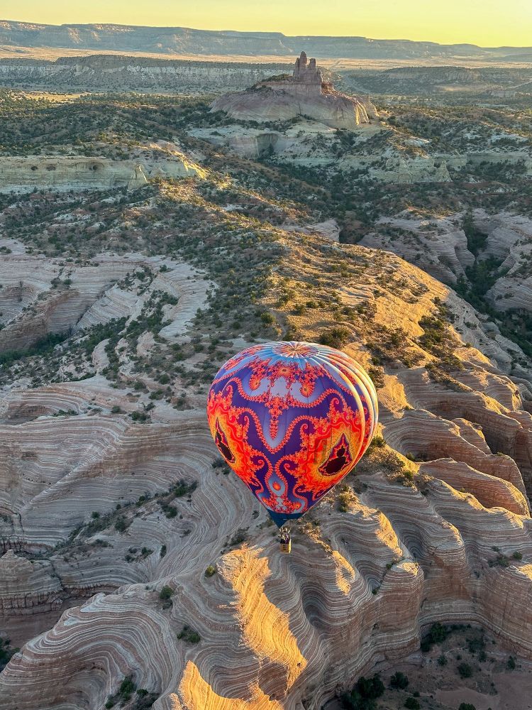 Fractal balloon over eroded sandstone canyons in front of Church Rock