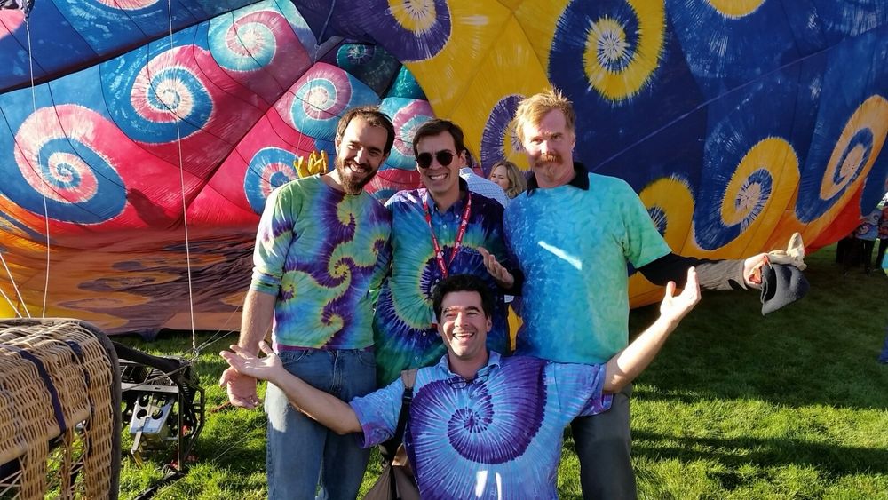 The artist surrounded by his friends / crew, all wearing precision tiedye, in front of Gloria Caeli - a hand built fully tiedyed hot air balloon