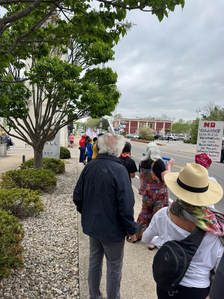 A crowd of people lining the street at a Hands Off demonstration. 