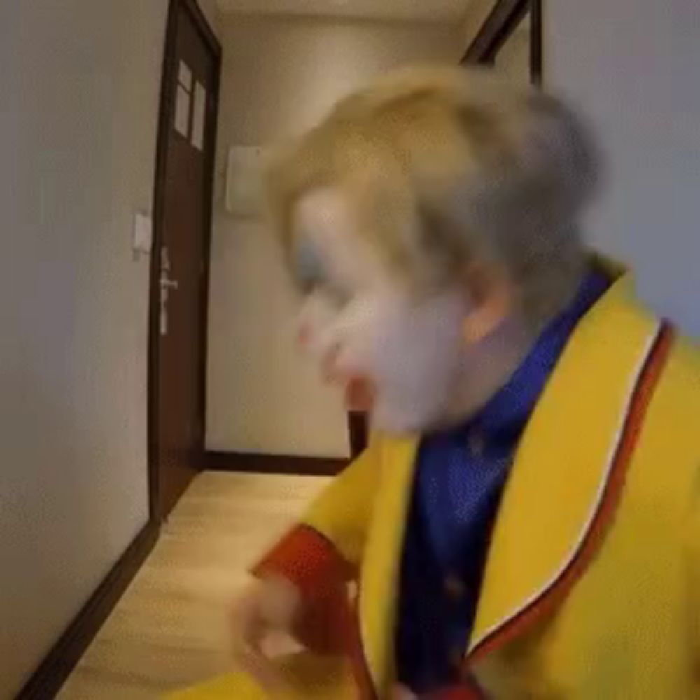 a man dressed as a clown is brushing his teeth with a stick