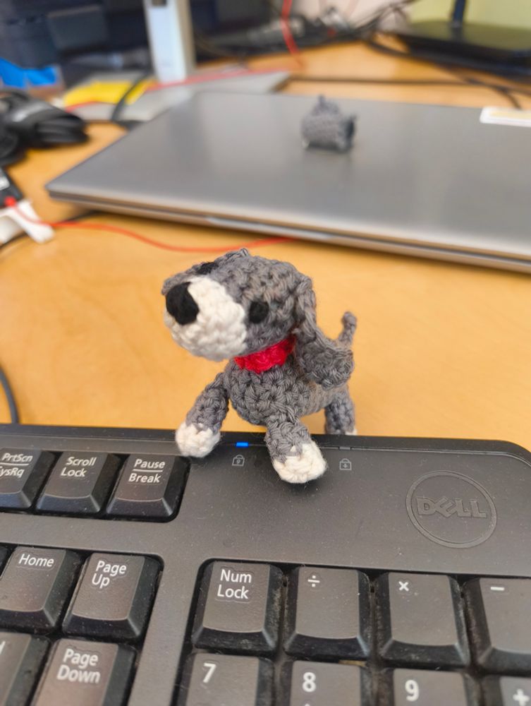 A crocheted grey and white dog with a red collar.