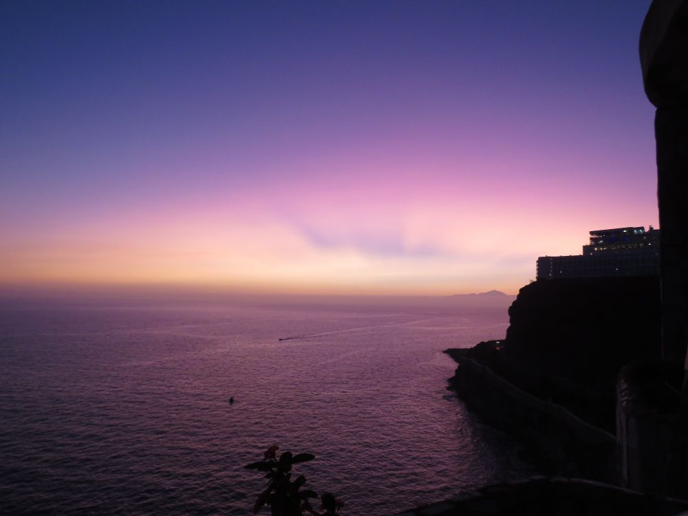 A purple sunset  over the sea, a distant island on the horizon