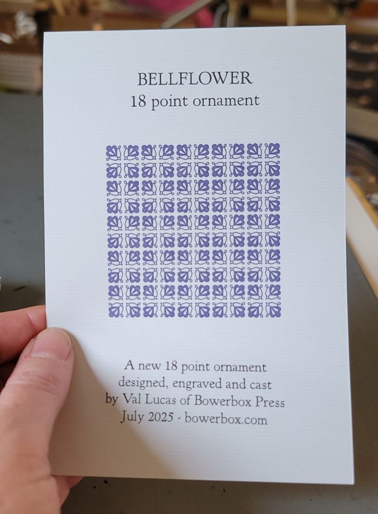 A hand holds a printed sheet with a purple pattern of newly designed and cast letterpress ornament, printed in a 10x10 grid.