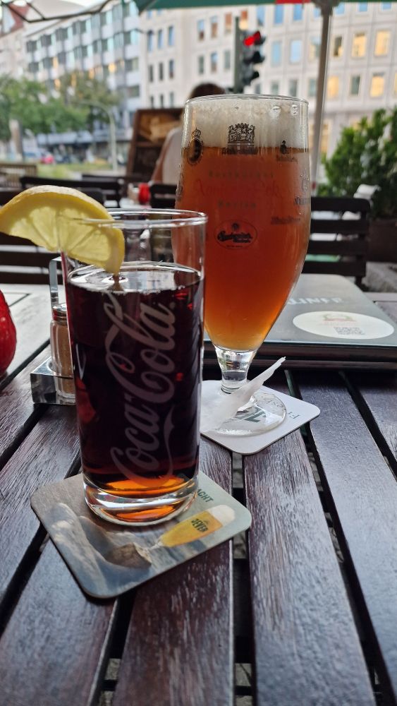 Ein Glas mit Cola und ein Glas mit Cola-Bier auf einem Tisch im Biergarten in Berlin.