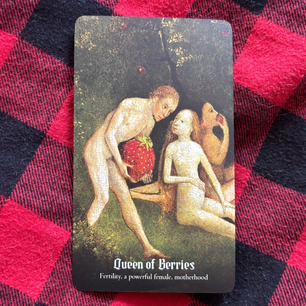A painting of a naked pregnant woman being brought a giant berry by a naked men as naked people sit in the background. On a red and black checked fabric background.