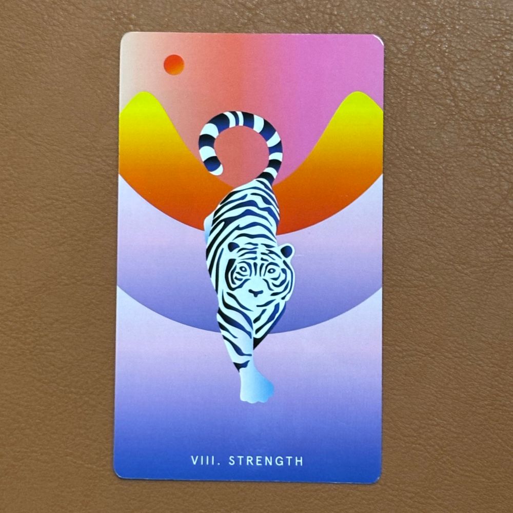 A stylised image of a white tiger prowling though orange and purple mountains. On a brown leather background.
