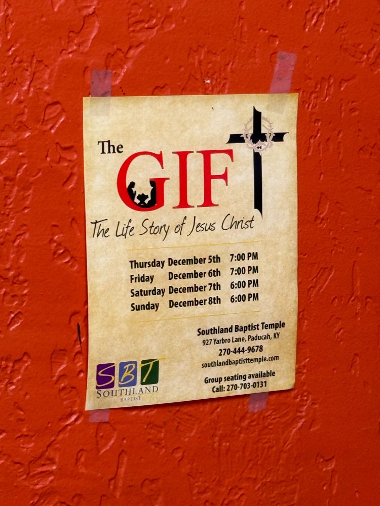 A poster advertising a holiday play, The Gift: The Life Story of Jesus Christ. The word “gift” is divided into two colors, GIF being red and the T being a black cross. 