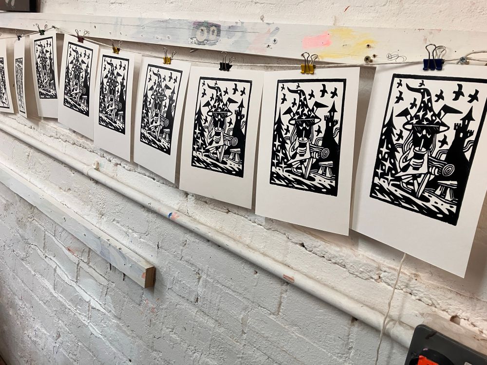 Lino prints hanging on a line from a wall whilst drying 