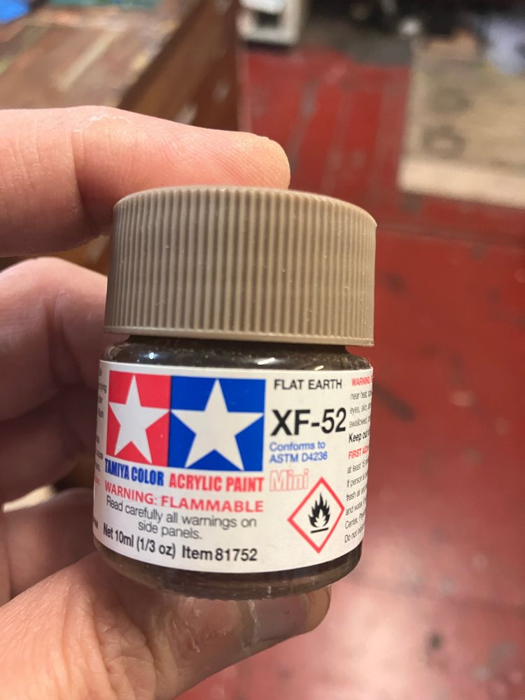 Tamiya acrylic model paint in a small glass pot. The colour is called flat earth