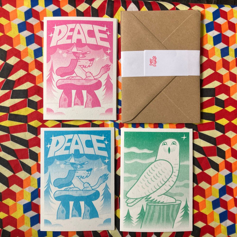 A set of 3 illustrated festive cards. The 2 designs are of an owl and the other is a dog with a bird on its head, both sat on a megalith with PEACE written above them.