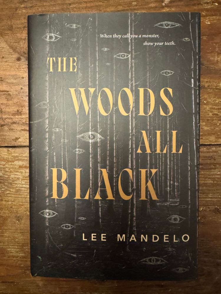 Cover of the book THE WOODS ALL BLACK showing disembodied eyes in a dark forest 