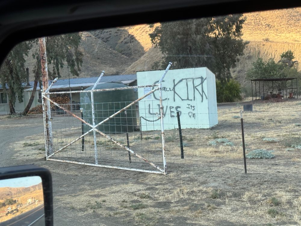 A shed in a barnyard along a rural highway has the phrase “Charlie Kirk Lives” and “It’s on” spray painted on it