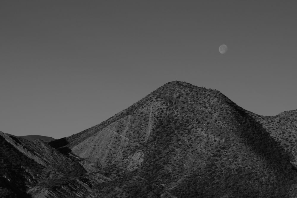 Black and white photo of moonrise over a mountain in the Tabernas Desert near Almeria, Spain