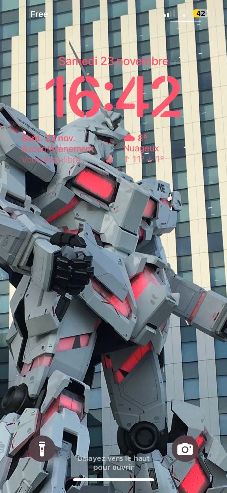 A screen capture of my lock screen. It is a picture of the Unicorn Gundam statue of Odaiba, Tokyo. The pink text match the accent colors of the statue.