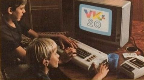 Two kids in front of a Vic 20. The left hand one has a mutant alien hand.
