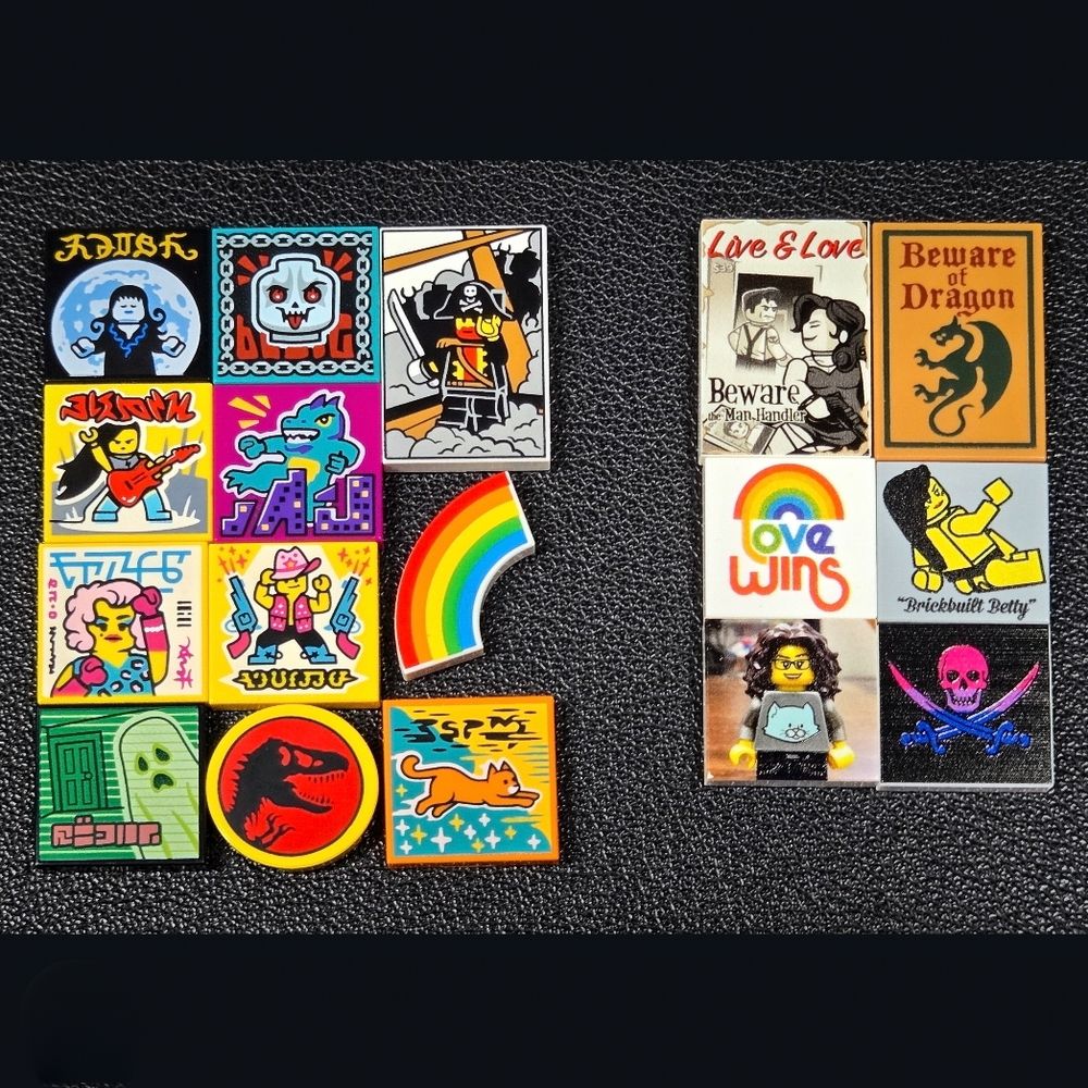 On the left side are 11 Lego tile pieces. A piece with goth girl and a moon behind her, and piece with a Lego skull with red eyes and tongue hanging out, a piece with a pirate and sword, a piece with a guy playing a guitar, a piece with  a godzilla creature, a rainbow piece, a piece with a pink haired woman that I think awesomely looks like a drag queen, a piece that has a cowboy boy wearing a pink hat and a vest with no shirt and two guns firing on either side, a piece with a Lego ghost, a round piece with the Jurassic Park logo, and a piece with an orange running cat. On the right side, 6 pieces. One piece says 
Live and Love Beware the Man Handler with a woman holding a gun looking at a man and done in a noir style, one piece that says beware of dragon with a dragon, one piece with a rainbow that say love wins, one with a Lego pinup girl that says Brickbuilt Betty, one with a minifigure wearing a cat shirt that represents me in Lego, and one with a pirate flag in the bisexual colors pink, purple, and dark blue.