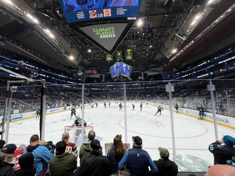 View of the players on the ice from behind the Seattle Kraken net during warmups.
