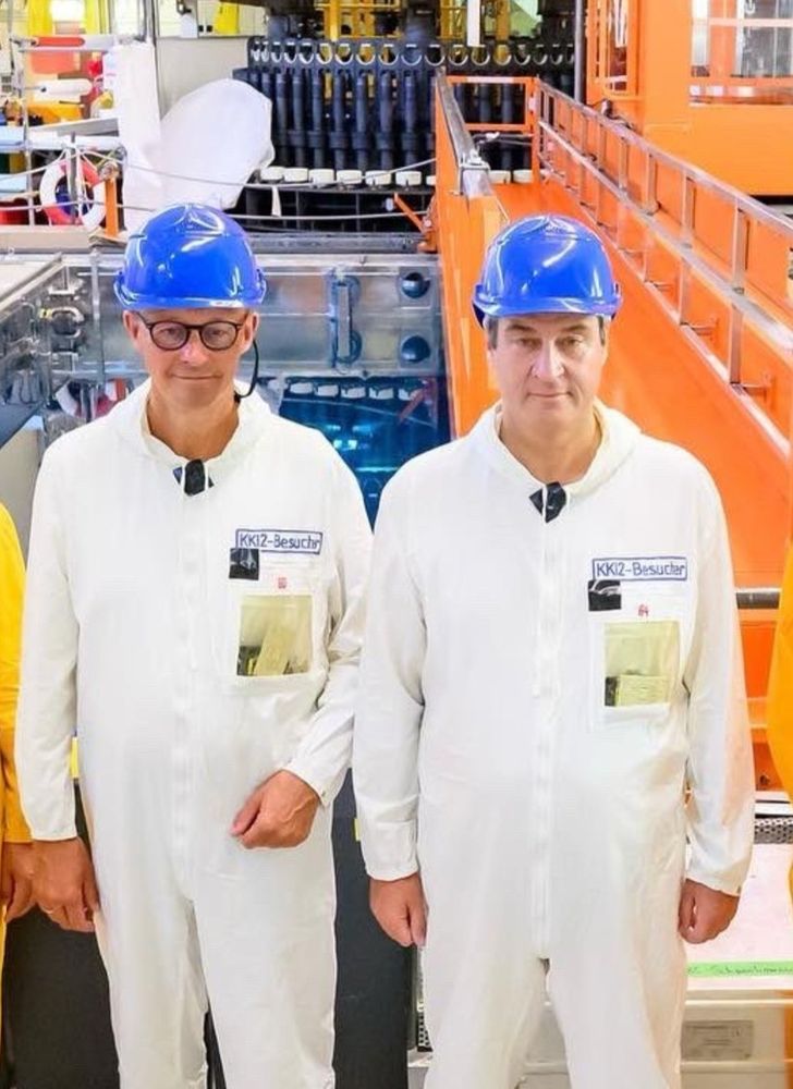 Zu sehen sind Friedrich Merz und Markus Söder im Schutzanzug in einem Atomkraftwerk
