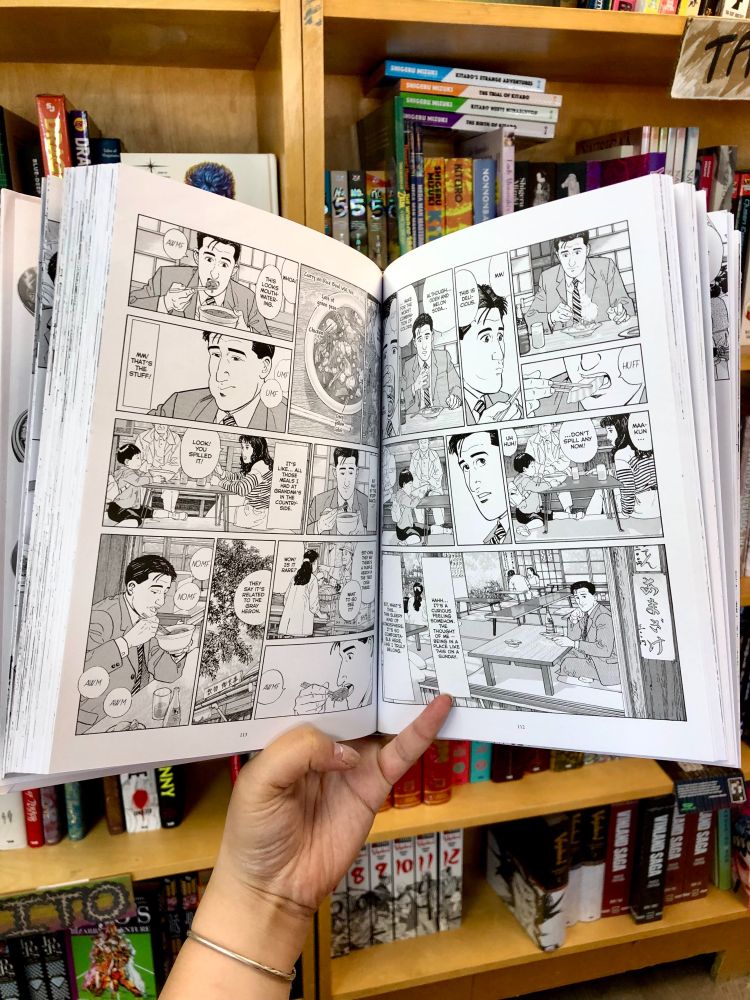 A hand holds open a spread from "The Solitary Gourmet"