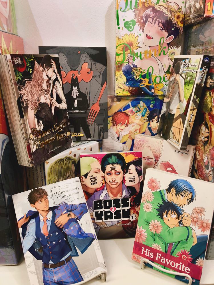 A selection of various boy's love manga and manhwa. Pictured are: Haberdashery Ginmokusei, Boss & Yasu, His Favorite, The Gardener's Favorite Poisonous Flower, Eat, Candy, Mask Danshi, Punch Drunk Love, and Twilight Out of Focus