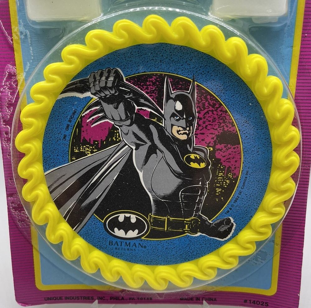 Close up photo of the Cake Topper from a Batman Returns Cake Decorator Set, with art of Batman holding his Super Batarang.