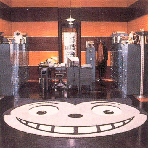 Production Photo from Batman Returns, featuring the office next to Max Shreck's Boardroom with it's GIANT Shreck's Cat Head Logo rug. This is the space where Max Shreck would confront Selina Kyle, & in the back is the window he would push her out of for accessing protected files.