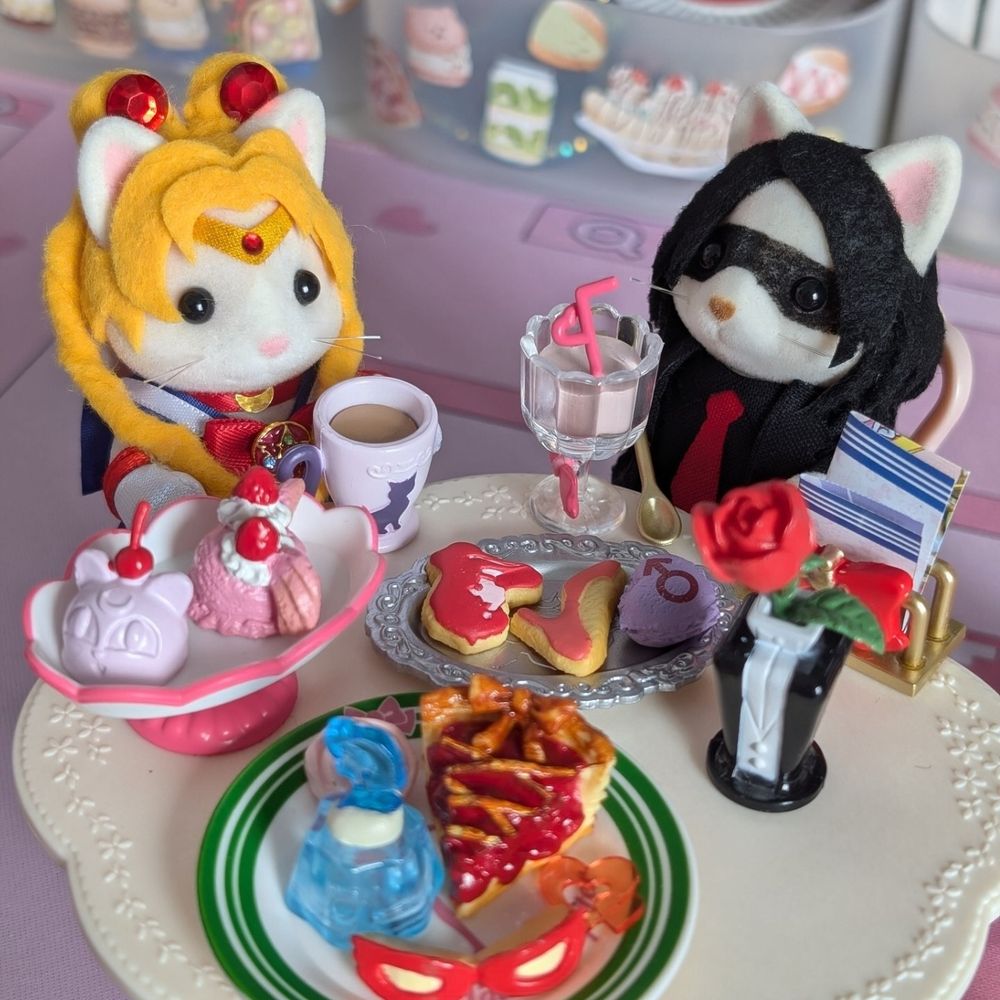 two cat calico critters customized to look like sailor moon and gerard way (revenge era). They're sitting around a table with pastries and desserts sailor moon themed.