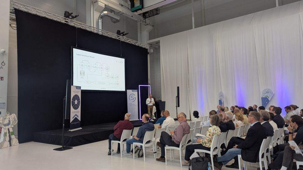 Picture of Dr. Kerem Kayabay presenting a slide with the title "Support the entire AI lifecycle" to an audience.