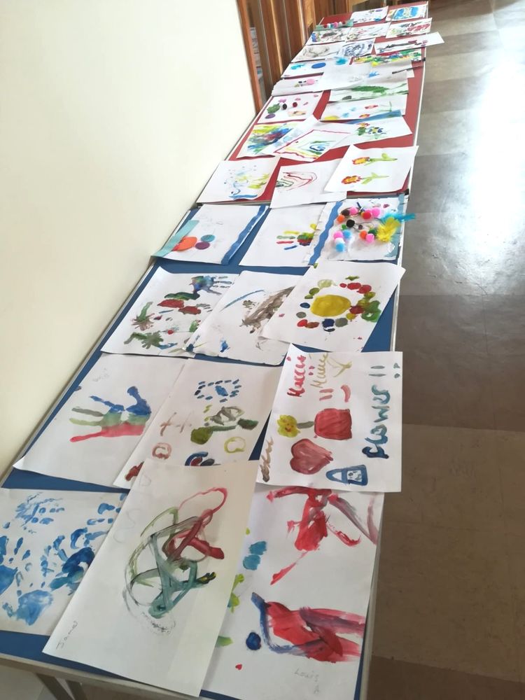 Tables covered in lots of children's paintings. 