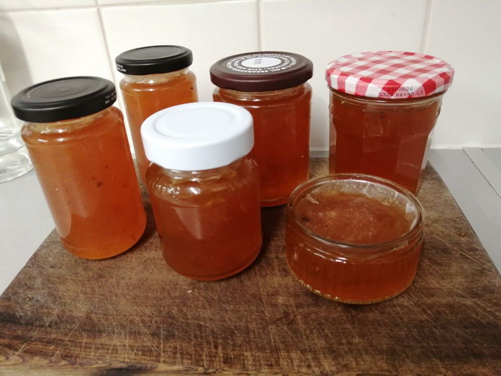 5 jars and one small glass dish full of plum jam. 