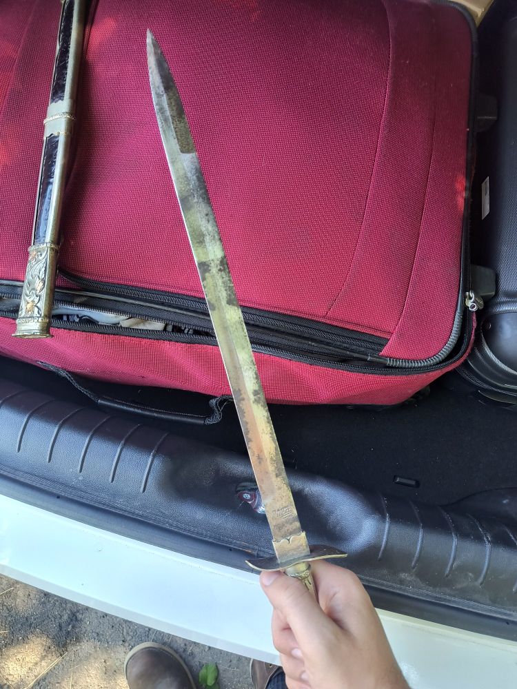 View of the knife's long blade. It has black rust on some parts.