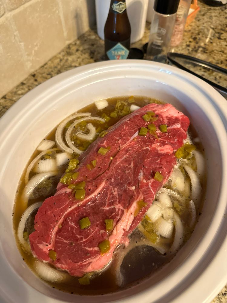 Chuck roast in a crock pot swimming in onions, garlic, green chiles and beer!