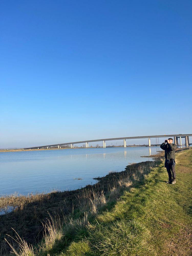 AJ standing on sea wall with the Sheppey Crossing in the background 