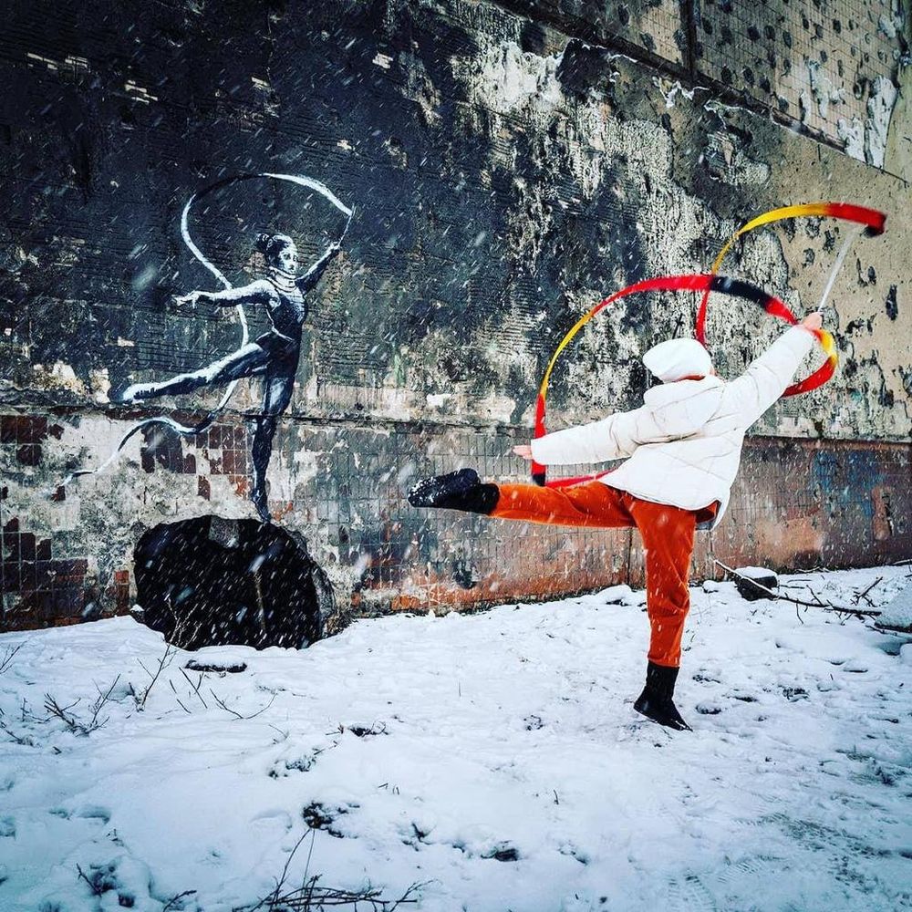 Petite fille ukrainienne dansant devant un dessin mural de Banksy.