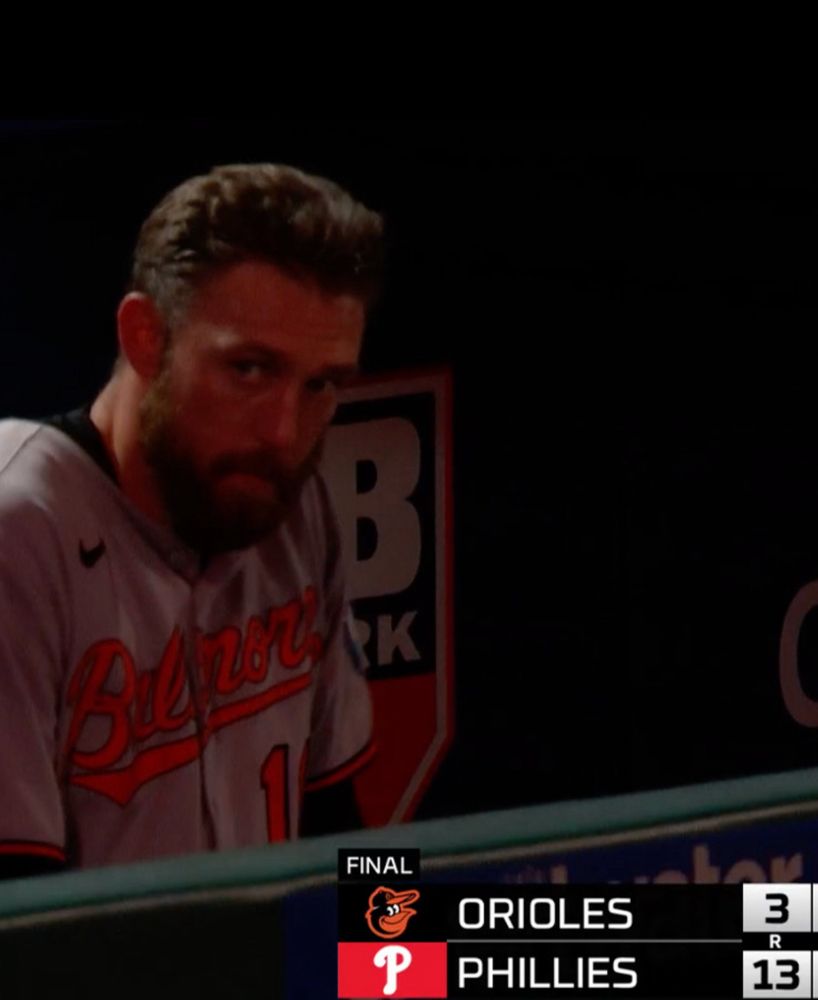 Jordan Westburg doing the Kubrick Stare in the Orioles dugout next to a score bug that shows the final 13-3 score of the loss to Philly 