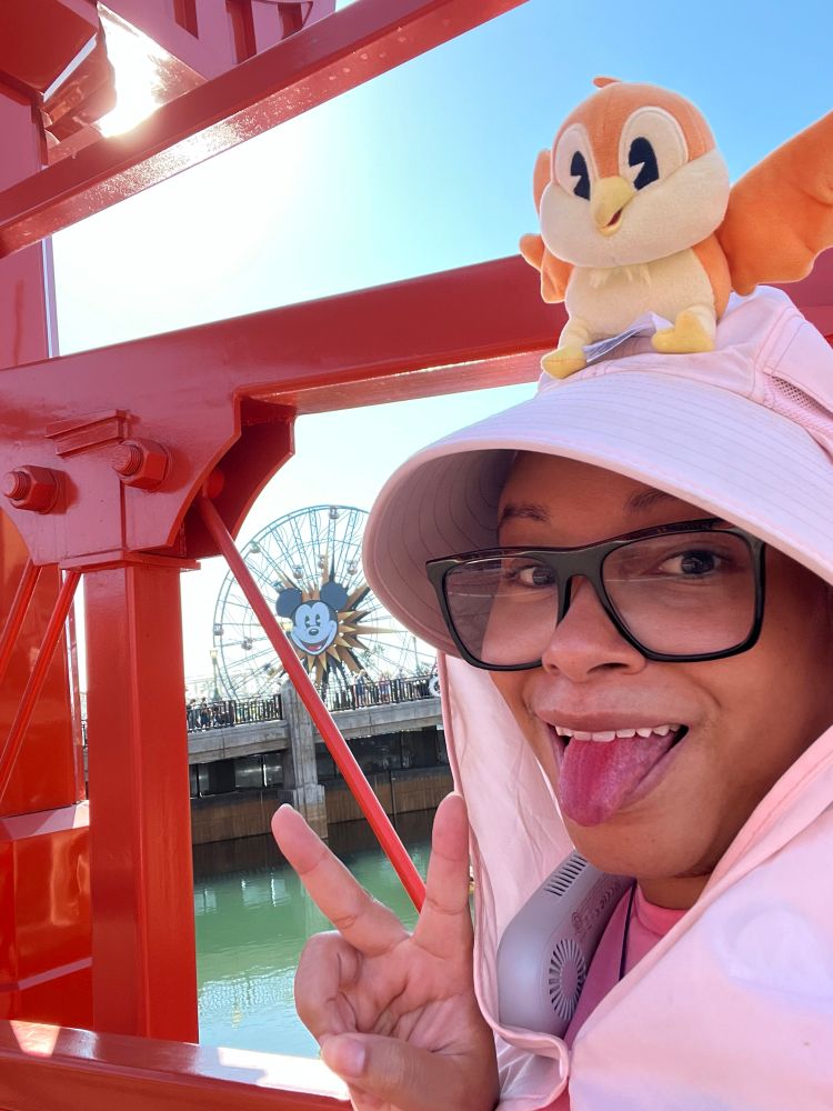 Me at Disney’s California Adventure, wearing a pink sun hat, tongue out, peace sign. 