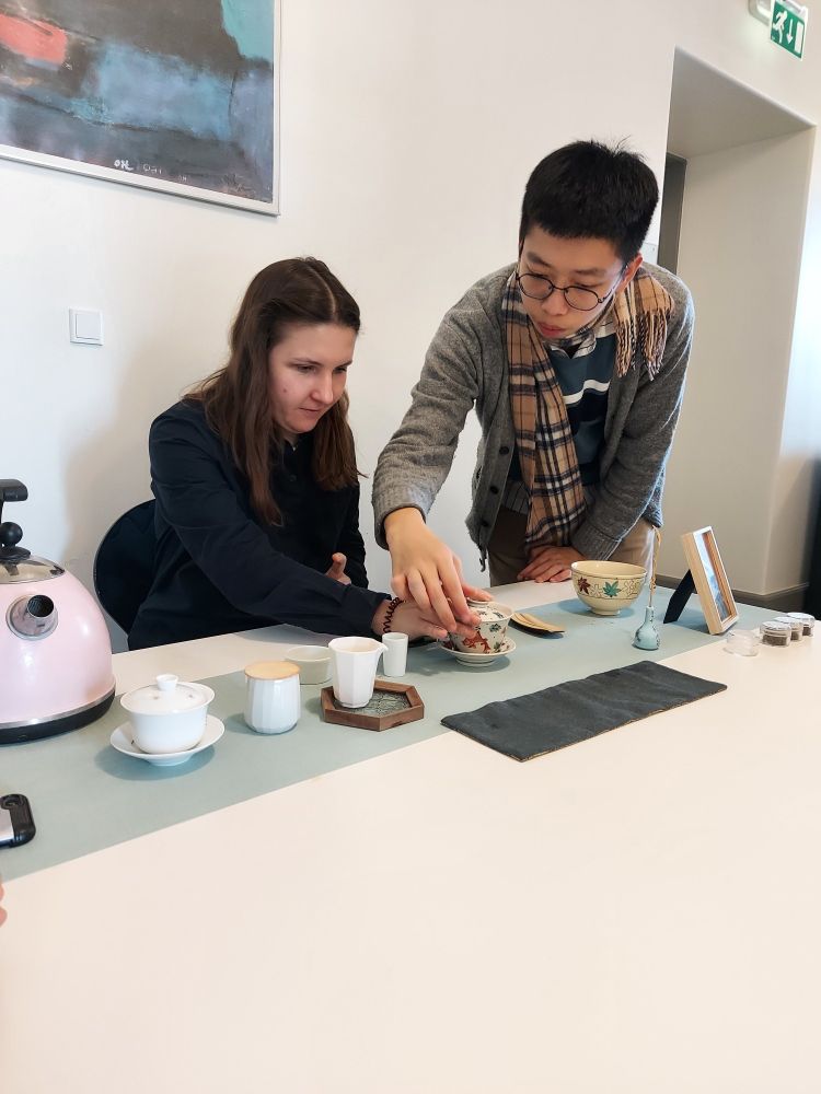 Aurelius Jiang of the 不知茶 organisation teaches a Copenhagen University researcher how to pour tea correctly from a covered bowl. The table is set with various accessories required for the Taiwanese tea ceremony.