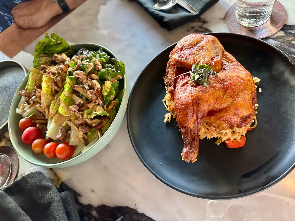A date and chili cashew salad with tahini dressing and a roasted half chicken on a bed of rice and vegetables. 