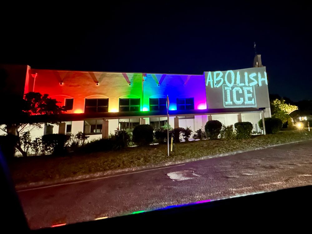 Allendale United Methodist Church which is lit up with rainbow lights and a projected image that says Abolish ICE